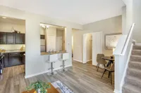 Modern open-concept apartment with sleek kitchen, cozy breakfast bar, and inviting dining nook, featuring elegant flooring and stylish decor.