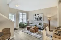 Elegant living room with modern decor, featuring a cozy gray sofa, green armchair, chic artwork, and natural light pouring through large windows.