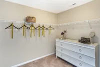 Elegant walk-in closet with spacious shelving, stylish hangers with decorative ribbons, and a chic white dresser adorned with accessories.