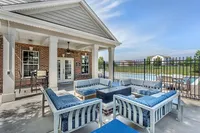 Charming outdoor patio area with elegant seating and a modern fire pit overlooking a sparkling pool, perfect for relaxing and entertaining.