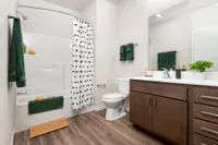 Modern bathroom with elegant wood cabinetry, sleek fixtures, and stylish green accents for a refreshing ambiance.