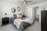 Inviting bedroom with modern decor, featuring a cozy bed with plush pillows, elegant side tables, and a stylish ceiling fan.