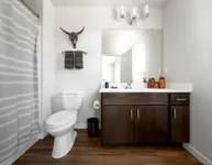 Contemporary bathroom featuring elegant dark wood cabinetry, modern fixtures, and a sleek white countertop.