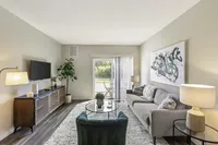 Chic living room with modern furniture, a cozy gray sofa, stylish decor, and a scenic balcony view.