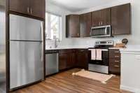 Modern kitchen with sleek stainless steel appliances, rich dark wood cabinetry, and stylish hardwood flooring.