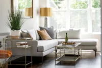 Inviting living room with a chic gray sectional sofa, plush cushions, and elegant glass tables, bathed in natural light.