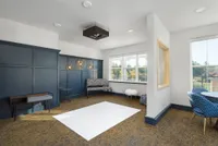 Modern sitting area with elegant navy paneling, stylish lighting fixtures, and ample natural light from large windows, perfect for relaxation and social gatherings.