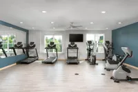 Modern fitness center with state-of-the-art treadmills, exercise bikes, and a scenic view through large windows.