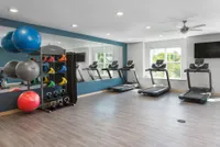 Modern fitness room with large mirrors, multiple treadmills, and vibrant exercise equipment, designed for a refreshing workout experience.