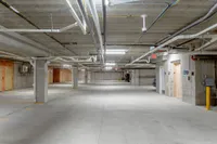 Spacious and well-lit underground parking garage with convenient access to elevators and ample space for vehicles.