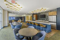 Elegant communal space featuring a modern kitchen with a long bar, stylish seating, and chic lighting, ideal for social gatherings and relaxing.