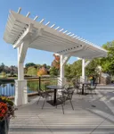Charming outdoor patio with elegant white pergola, overlooking a serene pond and lush greenery, featuring cozy seating perfect for relaxation.