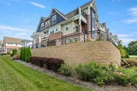Elegant multi-story apartment building featuring modern architecture with charming gables, lush landscaping, and spacious outdoor terraces.