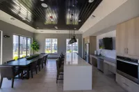 Elegant communal kitchen and dining area with sleek modern design, featuring a long dining table, high-end appliances, and abundant natural light.
