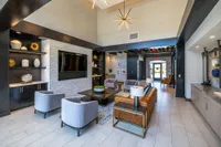 Elegant modern lobby featuring a sleek design with plush seating, decorative shelving, and a large TV, capturing a welcoming and stylish atmosphere.