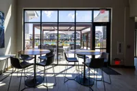 Chic apartment interior with modern seating overlooking a sunny pool area through large windows, perfect for relaxation and social gatherings.