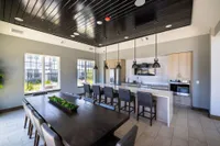 Contemporary dining area and kitchen with sleek black-and-wood interior, featuring ample natural light and stylish pendant lighting.