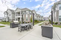 Charming apartment complex showcasing elegant architecture with spacious outdoor grilling and dining area, perfect for entertaining and relaxation.