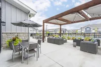 Chic outdoor patio area featuring stylish seating, a shaded dining set, and elegant pergola with string lights, perfect for relaxation and gatherings.