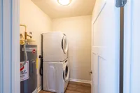 Bright laundry room with modern stacked washer and dryer, complemented by efficient water heater for convenience.