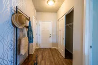 Inviting apartment entryway with chic wallpaper, stylish hat rack, and spacious closet.