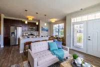Modern open-concept living area featuring sleek kitchen with stainless steel appliances, cozy seating, and natural light.