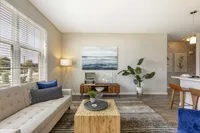 Modern living room with stylish decor, featuring a cozy beige sofa, vibrant artwork, and elegant wooden furniture.