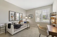 Inviting home office with stylish decor, featuring a cozy daybed, soft lighting, and a spacious desk near a sunlit window.