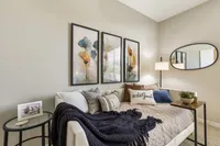 Cozy bedroom with elegant bedding, vibrant floral artwork, and stylish decor, offering a welcoming ambiance.