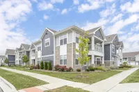 Bright and inviting apartment complex featuring charming gray facades and lush landscaping under a clear blue sky.