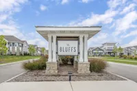 Inviting entrance to The Bluffs apartment community, featuring charming landscaping and modern architecture under a bright blue sky.