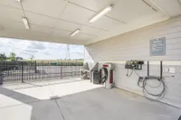 Modern outdoor car wash station with vacuum and hose facilities, featuring open landscape views under a bright sky.