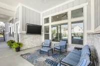 Chic outdoor patio featuring modern striped seating, a mounted TV, and vibrant greenery, perfect for relaxation and entertainment.