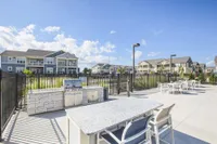 Bright and inviting apartment complex with modern outdoor barbecue area, perfect for entertaining, set against a backdrop of clear blue skies.