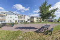Charming residential community with modern apartments, manicured lawns, and a welcoming park area under a sunny sky.