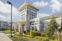 Elegant apartment complex featuring modern architecture with stone accents, lush landscaping, and a welcoming entrance.