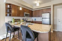 Modern kitchen with elegant granite countertops, stylish bar stools, and stainless steel appliances, creating a warm and inviting atmosphere.