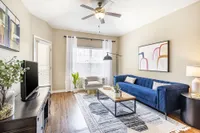 Inviting living room with elegant blue sofa, modern decor, and natural light pouring through large windows.