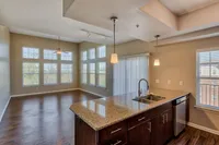 Bright and spacious open-concept living area with large windows, modern kitchen island, and elegant light fixtures.