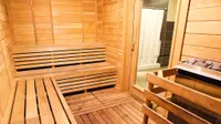 Luxurious wooden sauna room with bench seating and a stone heater, perfect for relaxation and wellness.