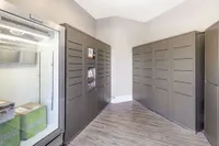 Modern package delivery room featuring sleek storage lockers and a glass-front fridge in a secure apartment complex.