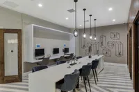 Modern communal workspace with sleek computers, geometric wall art, and chic hanging lights, perfect for productivity.