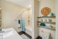 Modern bathroom with elegant decor, featuring a sleek sink, stylish shelving, vibrant accents, and a cozy bathtub area.