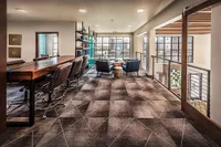 Modern lounge area with sleek leather seating, expansive windows, and a stylish geometric carpet design, perfect for relaxation or meetings.