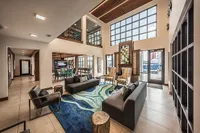 Luxurious open-concept living area with stylish modern furnishings, vibrant artwork, and ample natural light from floor-to-ceiling windows, perfect for elegant entertaining.