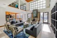 Spacious and modern living area with high ceilings, chic seating, large windows, and a vibrant fireplace, perfect for stylish gatherings.
