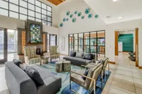 Bright and modern living area featuring large windows, chic lounge seating, and contemporary artwork in a spacious open layout.