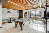 Chic recreational space with modern pool table, cozy seating area, and floor-to-ceiling windows providing abundant natural light.