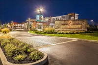 Vibrant evening view of Fishers District with illuminated signage, landscaped greenery, and modern buildings under a night sky.
