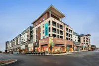 Modern mixed-use building with stylish retail stores and chic apartments above, located in a vibrant urban setting.